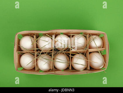 10 œufs de poule ferme blanc frais dans le récipient en bois fort avec hay sur fond vert, augmentation de la vue supérieure, juste au-dessus Banque D'Images