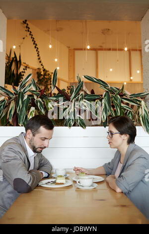 Vue de côté portrait de l'homme et de la femme de parler à table durant le repas dans le cafe Banque D'Images