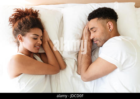 Photo de jeune africain couple aimant se trouve sur le lit à l'intérieur à la maison avec les yeux fermés. Banque D'Images
