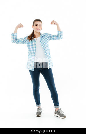 Drôle jeune fille brune portant des jeans et chemise à carreaux montrant les muscles isolated over white Banque D'Images