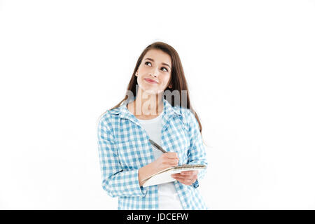 Portrait of a smiling woman making notes dans le bloc-notes et à l'écart à copie espace isolé sur fond blanc Banque D'Images