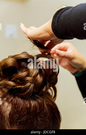 Coiffure femme coiffure rendant l'utilisation de fer à friser pour cheveux longs de jeunes femmes avec le smartphone en instituts de beauté Banque D'Images
