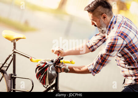 Businessman aller au travail en vélo. Il est la réparation de Vélo guidon sur une rue. Banque D'Images