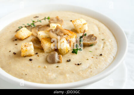 Crème de champignons soupe avec des croûtons, des herbes et épices sur fond blanc close up - régime végétarien végétalien maison repas biologiques soupe alimentaire Banque D'Images