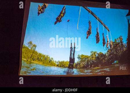 Merrick, New York, USA. 11 Juin, 2017. Au cours de la saison 2 de grain américain premiere, (au centre) à l'investiture CHRIS Édom, 48 ans, de Merrick, plonge dans l'eau après qu'il se retire après ripcord premier défi se termine. Tous les concurrents suspendu la tête en bas au-dessus et dans le lac jusqu'à ce défi s'est arrêté lorsque personne n'a renoncé. La cour arrière de l'affichage à Édom parti pendant la diffusion de l'épisode 1 de Fox network, émission de télé-réalité show a été projetée sur grand écran. Édom a été mise de 16 candidats sélectionnés pour une équipe que l'épisode. Credit : Ann Parry/ZUMA/Alamy Fil Live News Banque D'Images