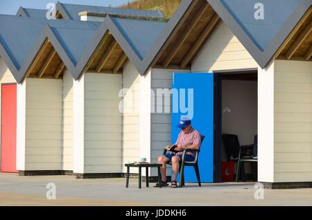 Swanage, Dorset, UK. 20 juin 2017. Météo britannique. Un homme assis à l'extérieur de sa cabane de plage à la station balnéaire de Swanage dans le Dorset sur un matin de soleil voilé chaud. Crédit photo : Graham Hunt/Alamy Live News Banque D'Images