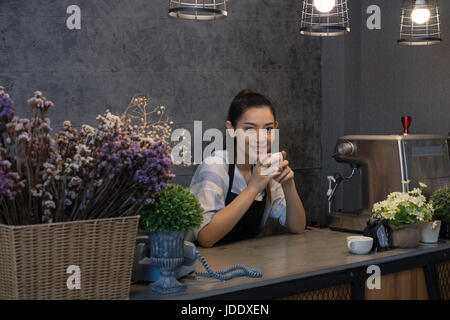 Propriétaire de petite entreprise à son café. happy asian woman standing au guichet. Jeune femme derrière le bar barista smiling in cafe Banque D'Images