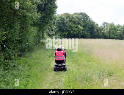 Une femme sur un scooter de mobilité Mobilité donnant accès à l'espace rural, Kent, England UK Banque D'Images