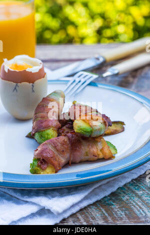 Des oeufs à la coque avec pancetta soldats d'avocat sur la table dans le jardin Banque D'Images