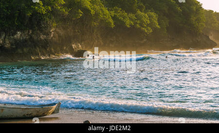 Les enfants surfent sur les vagues dans le coucher du soleil la lumière, Belle Baie Cristal, Nusa Penida, Bali Banque D'Images