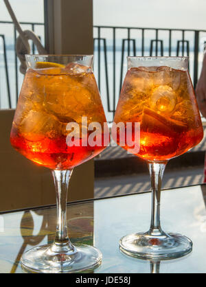 Serveur a préparé les esprits de l'été avec cocktail Aperol Aperol, prosecco, des cubes de glace et d'orange dans un verre de vin, prêt à boire sur la terrasse ensoleillée avec vue sur la mer Banque D'Images