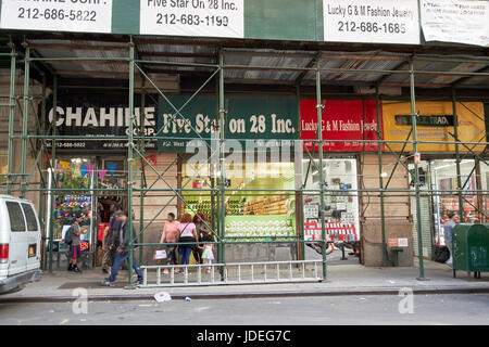 Les échafaudages sur un trottoir à l'extérieur de petits magasins de mode bon marché importés nomad New York City USA Banque D'Images