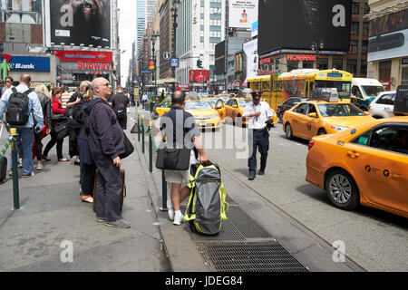 Les gens qui attendent les taxis jaunes à arrêter au taxi sur la 7ème avenue à l'extérieur de Penn Station New York USA Banque D'Images