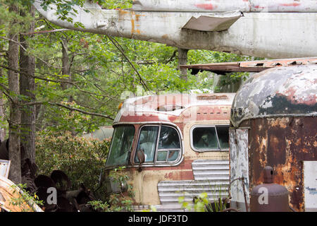 Les vieux bus de rouille et des avions en région boisée junkyard. Banque D'Images