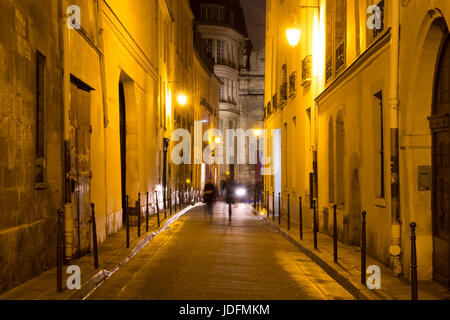 Deux femmes à pied dans la nuit sur la motion floue l'une des ruelles du quartier du Marais à Paris. C'est la nuit. Le quartier héberge de nombreux bu Banque D'Images