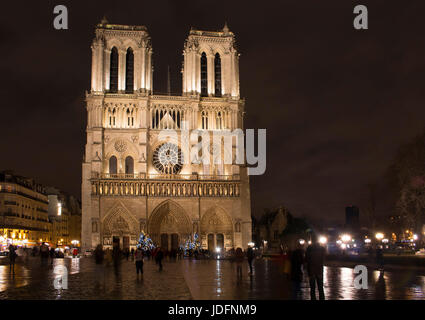 Les gens sont en mouvement flou autour de la cathédrale Notre Dame nuit à Paris l'hiver. Banque D'Images