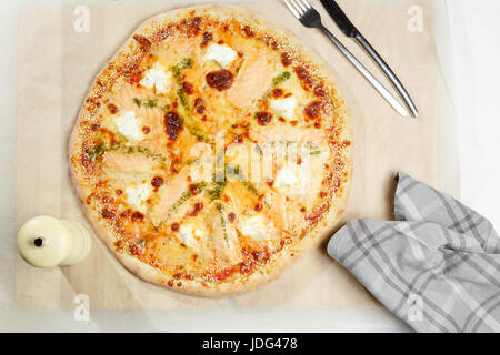 Pizza italien avec le saumon sur un papier. Serviette de table, fourchette et couteau dans un restaurant. Banque D'Images