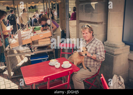 Un homme avec un chien à la terrasse d'un café, le marché des producteurs de Stroud, Gloucestershire, Royaume-Uni Banque D'Images