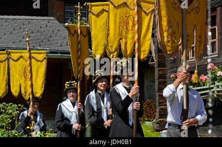 Les femmes en costume portant des bannières religieuses à la procession du Corpus Christi, Blatten, Lötschental, Valais, Suisse Banque D'Images