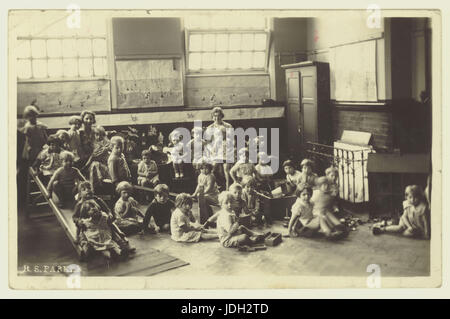 Années 1920 Carte postale de Saint Andrews School, Homer Street, Manchester - nourrissons ou enfants maternelles dans la salle avec l'équipement de jeux, UK Banque D'Images