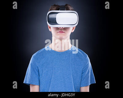 Happy teen garçon portant des lunettes de réalité virtuelle à regarder des films ou jouer à des jeux vidéo. Cheerful smiling adolescent à lunettes en RV. Ex enfant drôle Banque D'Images
