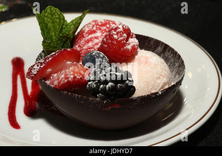 Fruits au chocolat sorbet en shell sur le plat blanc avec sirop de framboise Banque D'Images