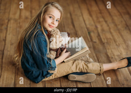 Smiling little Girl with teddy bear holding book, education kids concept Banque D'Images