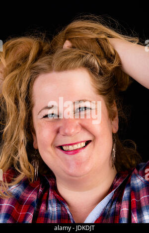Portrait d'une jolie lumière européenne surpondérés red haired femme rouge avec chemise bûcheron - voir sur la tête, studio shot en face de black backgrou Banque D'Images