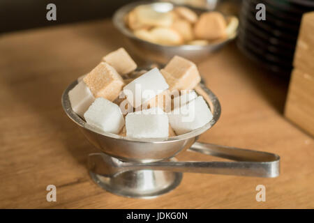 Close up de sucre de canne blanc et noir les cubes dans un bol en métal Banque D'Images