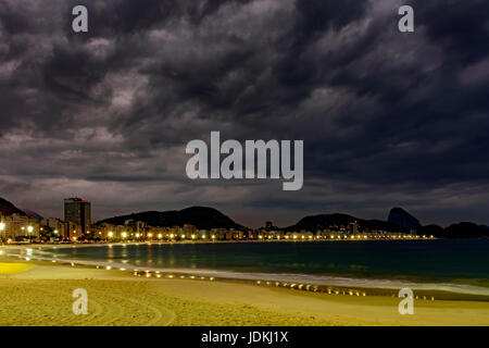 La plage de Copacabana et le Pain de Sucre vu la nuit avec ses bâtiments, l'éclairage, la mer, les collines et les contours Banque D'Images