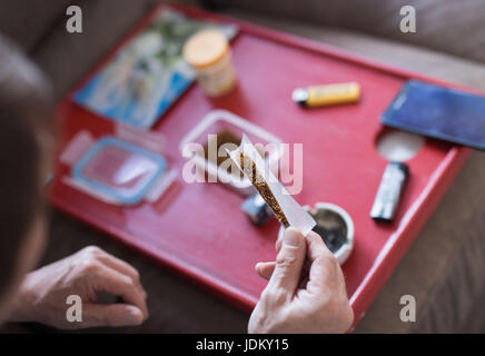 Nieder-Roden, Allemagne. 29 mai, 2017. Frank-Josef Ackerman roule une cigarette de cannabis dans sa maison à Nieder-Roden, Allemagne, 29 mai 2017. Il cultive ses propres plants de cannabis dans une penderie dans sa maison. Le patient de la douleur est l'un des rares autorisé à cultiver du cannabis, même si seulement pour la consommation personnelle. La Cour constitutionnelle fédérale a décidé que le cannabis cultivé par l'auto-thérapie pour malades dans leurs propres maisons ne doivent pas être confisqués par la police tant qu'ils remplissent certaines conditions préalables. Photo : Frank Rumpenhorst/dpa/Alamy Live News Banque D'Images