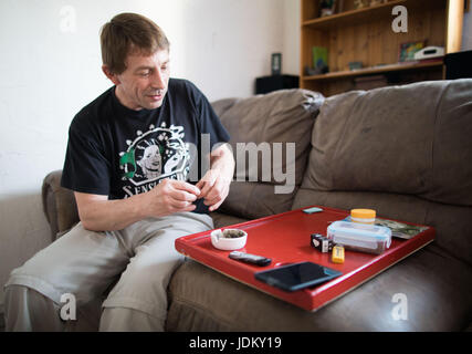 Nieder-Roden, Allemagne. 29 mai, 2017. Frank-Josef Ackerman roule une cigarette de cannabis dans sa maison à Nieder-Roden, Allemagne, 29 mai 2017. Il cultive ses propres plants de cannabis dans une penderie dans sa maison. Le patient de la douleur est l'un des rares autorisé à cultiver du cannabis, même si seulement pour la consommation personnelle. La Cour constitutionnelle fédérale a décidé que le cannabis cultivé par l'auto-thérapie pour malades dans leurs propres maisons ne doivent pas être confisqués par la police tant qu'ils remplissent certaines conditions préalables. Photo : Frank Rumpenhorst/dpa/Alamy Live News Banque D'Images