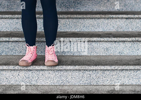 Femme jambes en guêtres noires et rose sneakers debout sur une scène de Pierre Banque D'Images