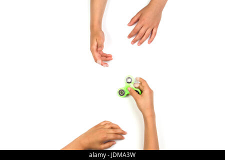 La main de l'enfant fidget spinner pour un autre enfant les mains sur fond blanc. Vue d'en haut Banque D'Images