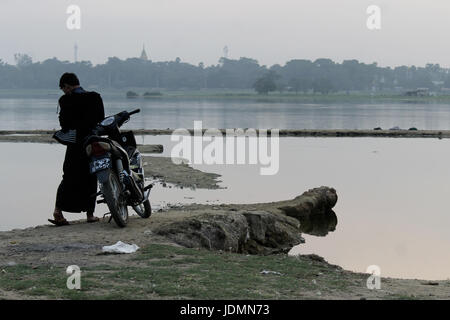 U-Bein Bridge/Amarapura - Myanmar 22 Janvier 2016 : un jeune homme birman avec son scooter à la rive du lac Taungthaman près d'u-bein Bridge. Banque D'Images