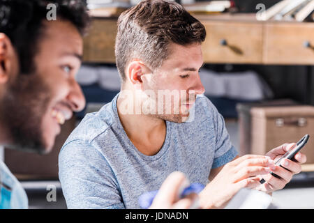 Les jeunes professionnels de bureau de petite entreprise, man using smartphone Banque D'Images