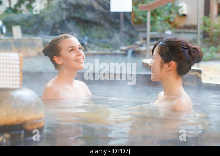 Caucasian woman avec ami japonais echelle à traditionnel Hot spring, Tokyo, Japon Banque D'Images