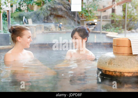 Caucasian woman avec ami japonais echelle à traditionnel Hot spring, Tokyo, Japon Banque D'Images