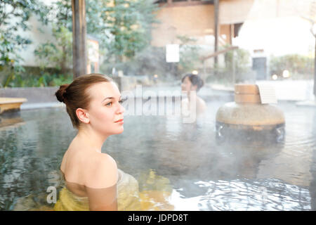 Caucasian woman avec ami japonais echelle à traditionnel Hot spring, Tokyo, Japon Banque D'Images