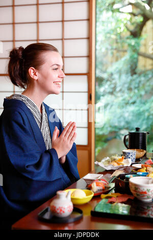 Caucasian woman wearing yukata manger au ryokan traditionnel, Tokyo, Japon Banque D'Images