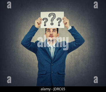 Portrait of young businessman pensée confuse, cherche une solution à la recherche, tenant un papier sur la tête avec tirées d'interrogation, isolé sur wa gris Banque D'Images