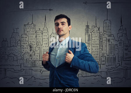 Jeune homme sérieux agissant avec courage comme un super héros et de déchirer sa chemise au large d'essayer de sauver la ville de problèmes économiques. Confiance Banque D'Images