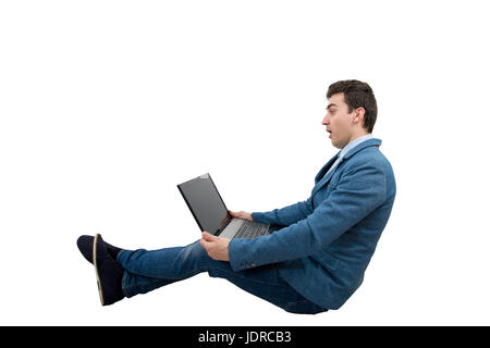 Surpris jeune businessman looking at a laptop monitor en restant assis. Banque D'Images