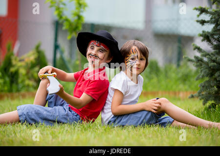 Deux enfants, frères, peint que tiger et pirate, jouer ensemble dans le jardin, s'amuser, printemps Banque D'Images