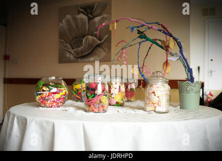 Les bocaux en verre remplis de bonbons à une table avec un tissu blanc Banque D'Images