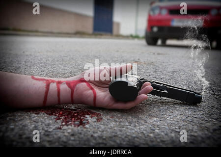 L'homme avec l'arme à la main est tachée de morts dans la victime de meurtre d'asphalte Banque D'Images