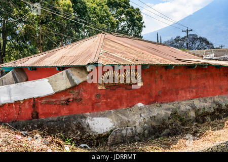 Antigua, Guatemala - mars 26, 2017 : mur rouge de la maison par la rivière à sec avec volcan agua derrière en ville coloniale et site du patrimoine mondial de l'UNESCO Banque D'Images