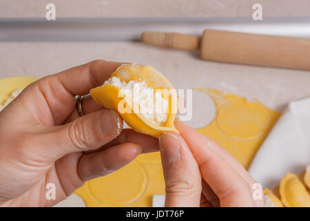 Vue rapprochée de woman's hands la préparation pour la cuisine vareniki, boulettes, pierogi avec du fromage cottage ou une pâte alimentaire traditionnelle ukrainienne. Pi Matériel roulant Banque D'Images