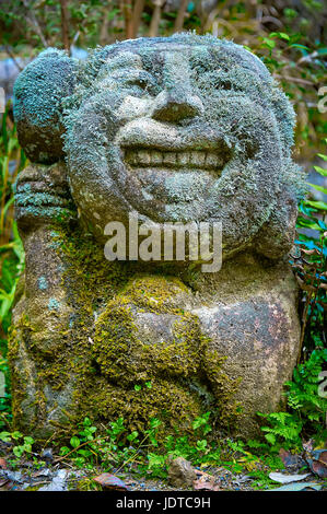 TEMPLE OTAGI, KYOTO, JAPON - 19 octobre 2016 : une statue en pierre sculptée avec visage souriant. L'ensemble de la statue est couverts de mousse et de petites feuilles. Banque D'Images