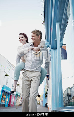 Man carrying girlfriend on city street Banque D'Images